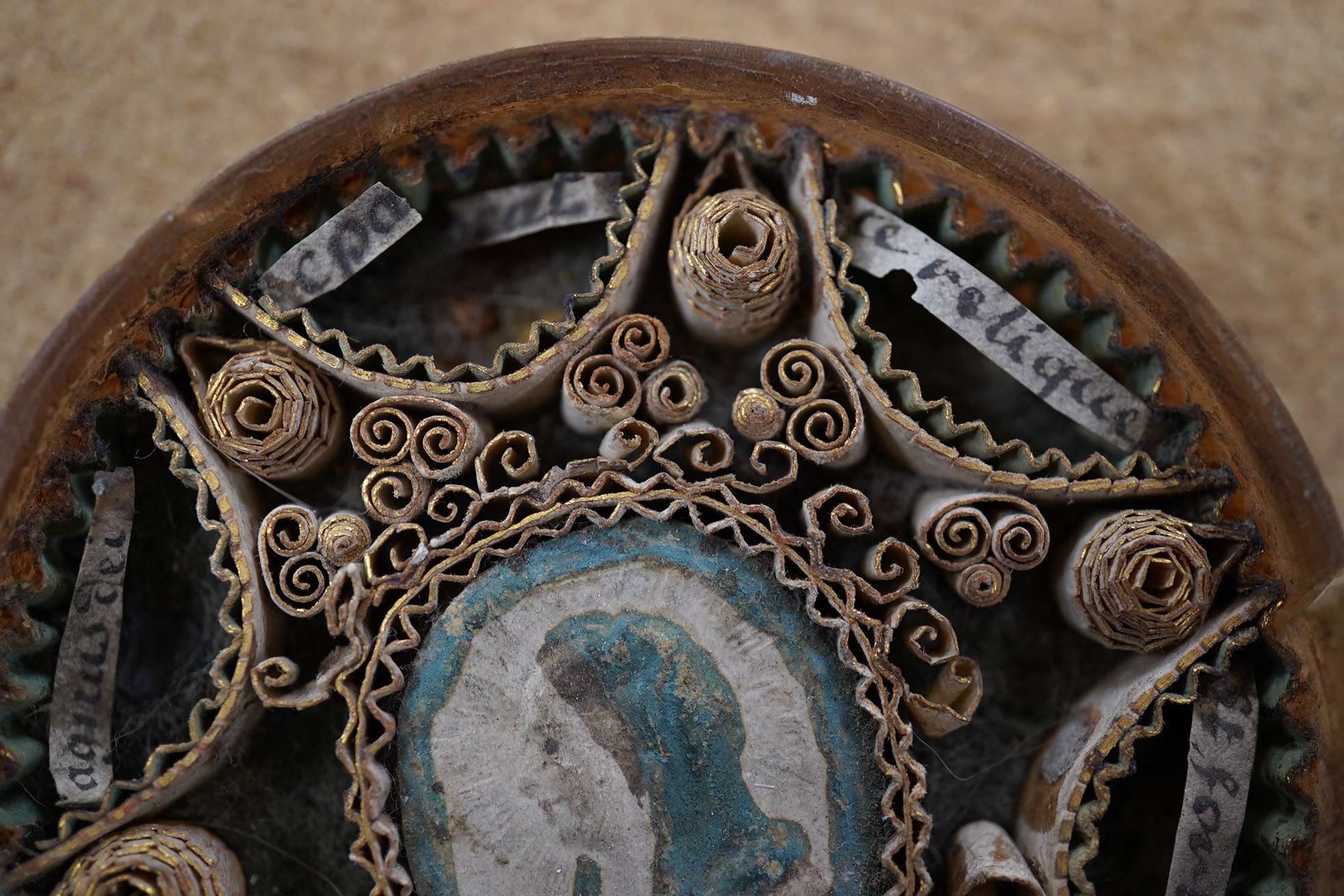 An early 19th century devotional reliquary rolled paper roundel, 7cm in diameter. Condition - fair